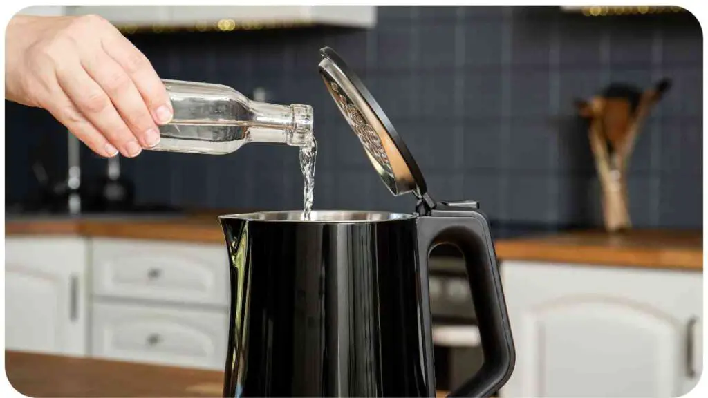 a person pours water into an electric kettle.